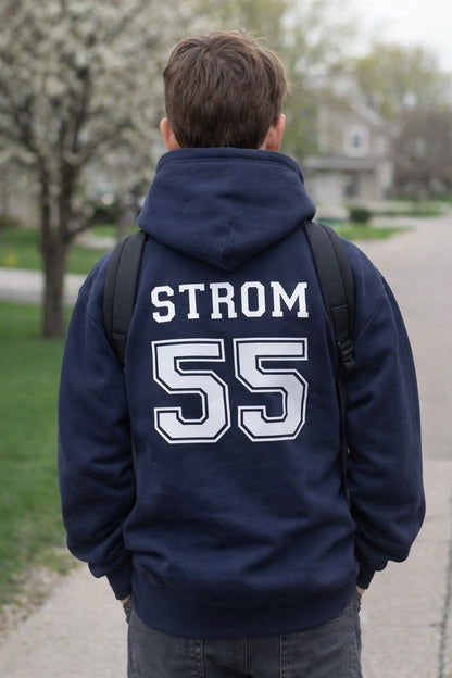 Person wearing a navy blue hoodie with 'STROM 55' printed on the back, standing outdoors.
